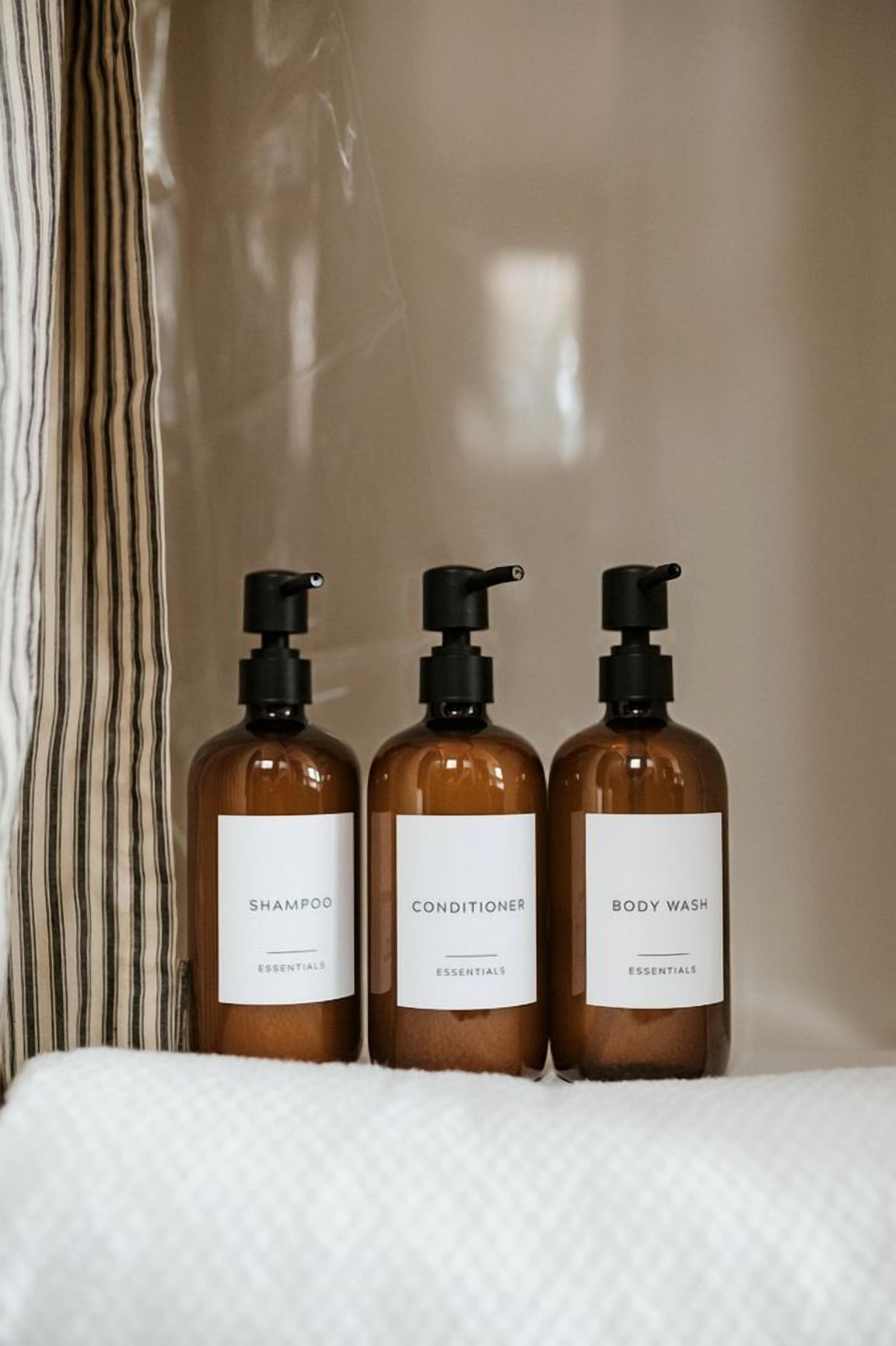 Three bottles of shampoo, conditioner, and body wash on a white surface.