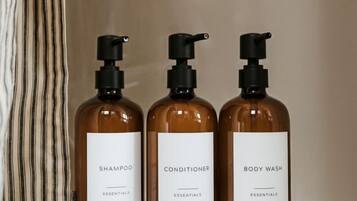 Three bottles of shampoo, conditioner, and body wash on a white surface.