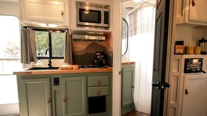 Una cocina compacta con microondas, estufa y armarios.