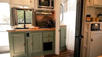 A compact kitchen with a microwave, stove, and cabinets.