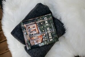 Ein Buch mit dem Titel 'Tiny Homes', auf dem ein Haus abgebildet ist, liegt auf einer flauschigen weißen Oberfläche.