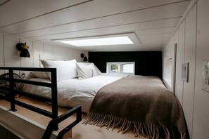 Un lit superposé avec une tête de lit, une fenêtre et un lit avec une couverture.