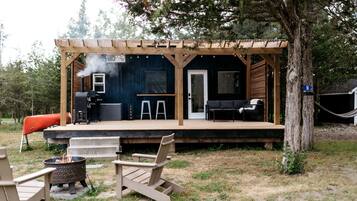 A wooden deck with a grill, outdoor seating, and a covered area with a door.
