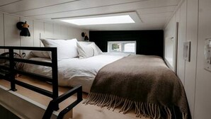 Cama litera con cabecera, ventana y ropa de cama.