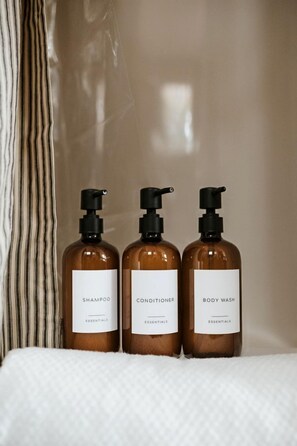 Trois bouteilles de shampoing, d’après-shampoing et de gel douche, posées sur une surface blanche.