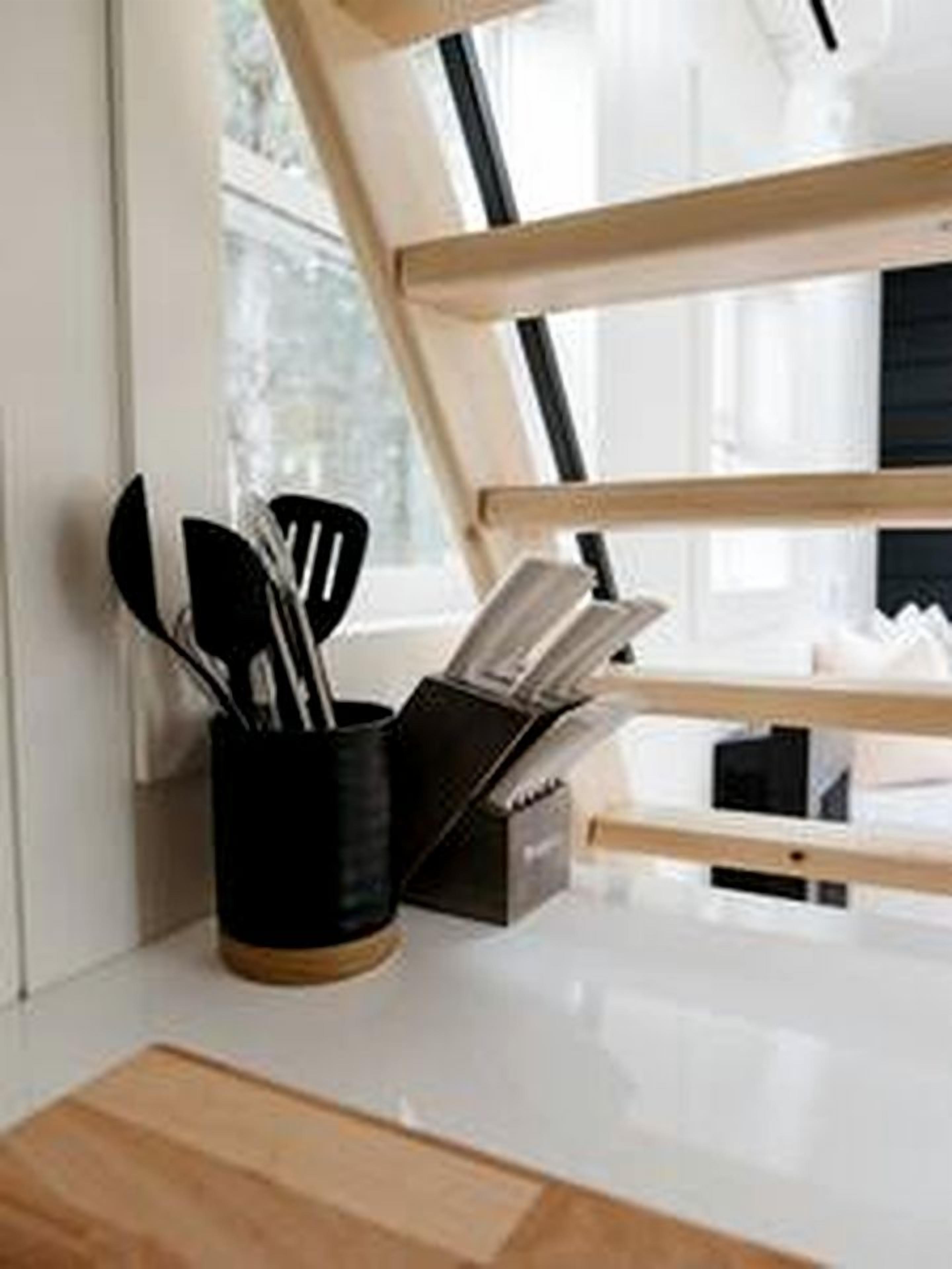 A kitchen with a wooden countertop, a black utensil holder, and a window with a view.