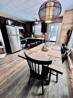 A modern kitchen with a large island, stainless steel appliances, and a unique spherical pendant light.
