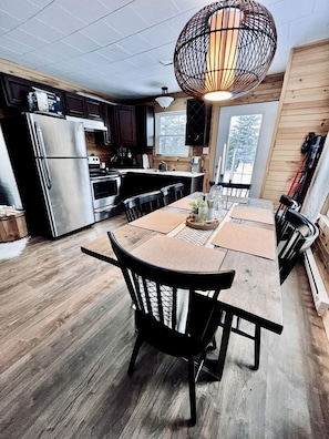 A modern kitchen with a large island, stainless steel appliances, and a unique spherical pendant light.