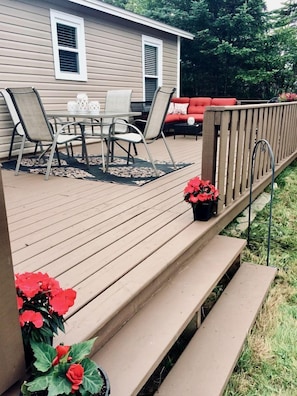 A deck with outdoor furniture, a railing, and potted plants.