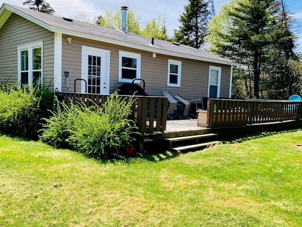 A single-story house with a front deck, a chimney, and a small porch area.