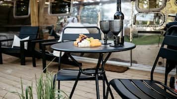 An outdoor patio with a table set for two, a bottle, and glasses.