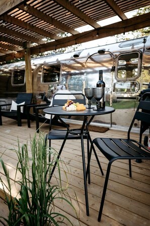 Une terrasse extérieure avec une table dressée pour deux personnes, une bouteille et des verres.