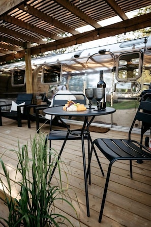 Patio esterno con tavolo apparecchiato per due, una bottiglia e dei bicchieri.