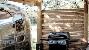 A wooden deck with a grill and a vintage camper.