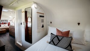 Ein kleines, helles Schlafzimmer mit Bett, Nachttisch und Spiegel.