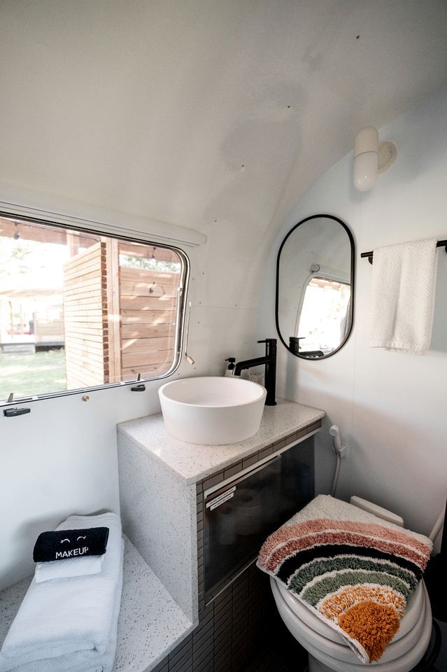 A compact bathroom with a white sink, a mirror, a towel rack, and a window.