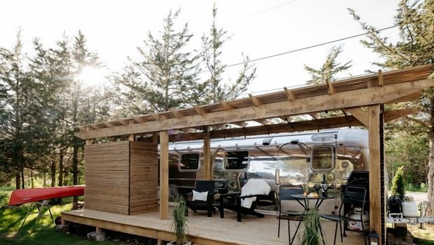 Eine Holzterrasse mit Sitzgelegenheiten und Grillplatz.