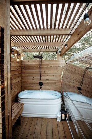 Eine Holzsauna mit zwei Whirlpools, einer hölzernen Sitzbank und einer Profildecke.