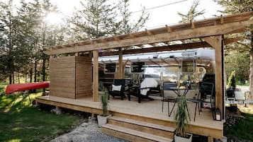 A wooden deck with outdoor seating and a grill area.