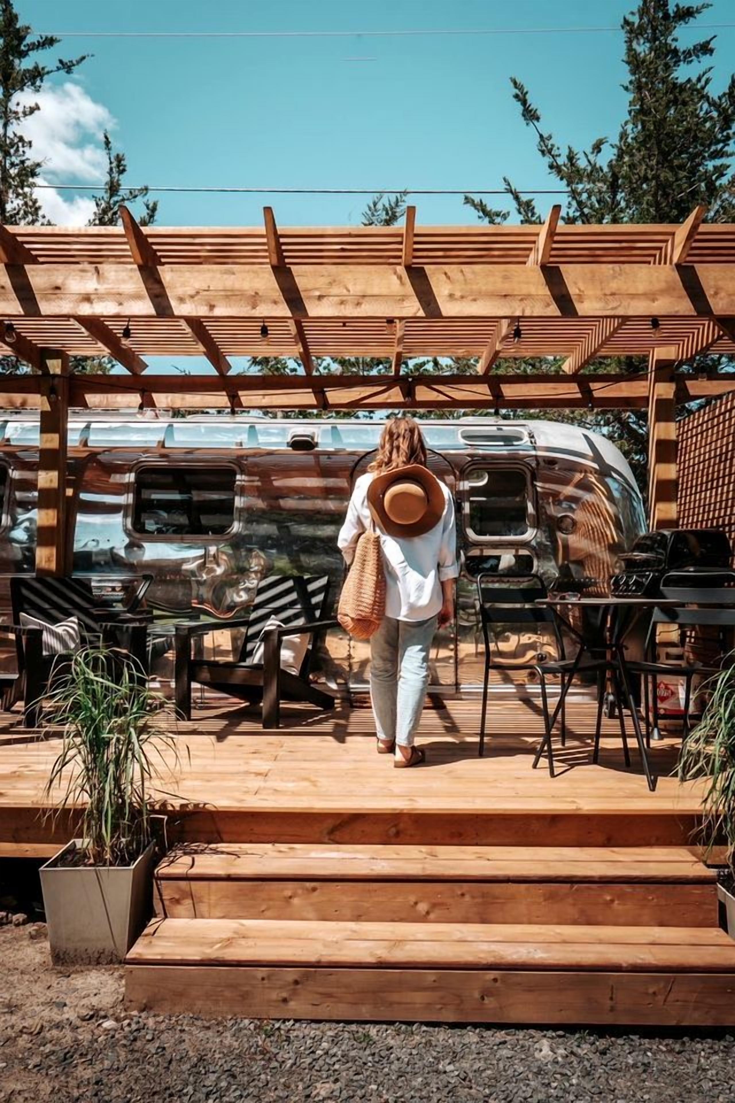 A person walking towards a campervan under a wooden pergola.