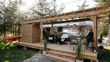 A wooden deck with outdoor seating and a grill area.