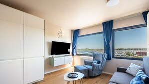 En moderne stue med et fladskærms-tv, en sofa, en lænestol og et lille bord.