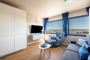 Un soggiorno moderno con una TV a schermo piatto, un divano, una poltrona e un tavolino.