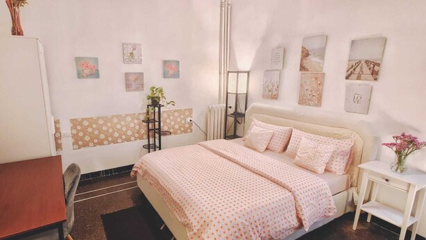 Un dormitorio con una cama, un escritorio, un radiador y adornos en la pared.