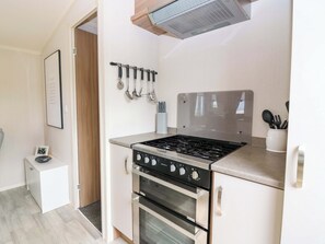 A compact kitchen with a gas stove, oven, and a small countertop. - 18 Eden Heights (St. Andrews)