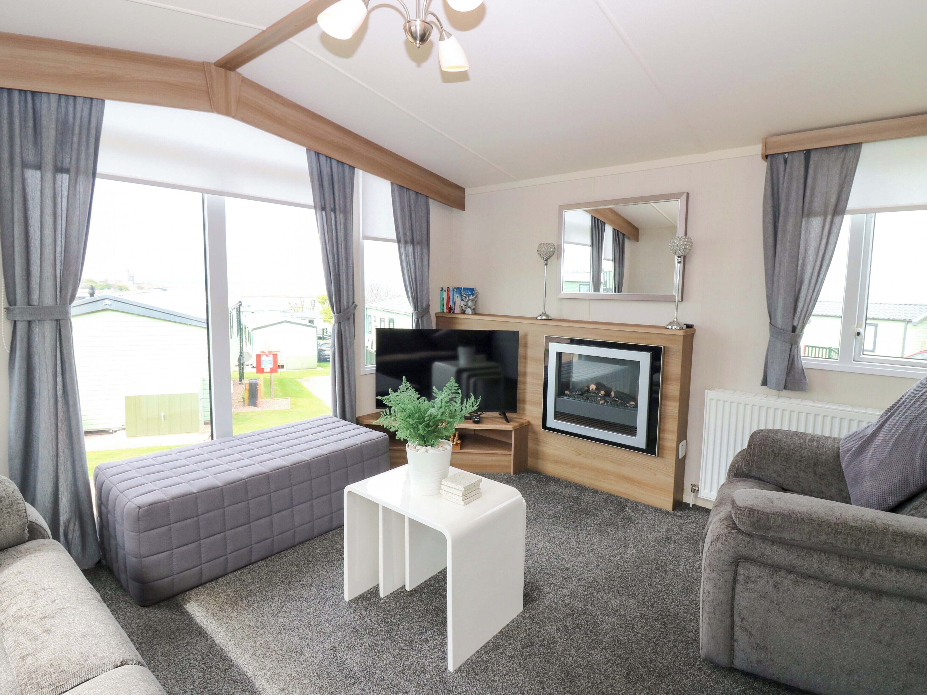 A living room with a sofa, a white coffee table, a fireplace, and a television.