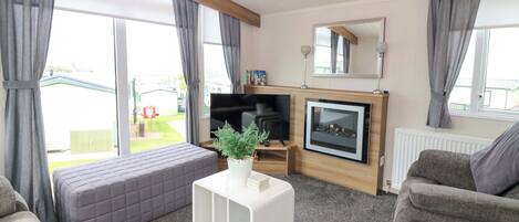 A living room with a sofa, a white coffee table, a fireplace, and a television.