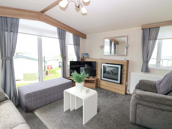 Una sala de estar con sofá, una mesa de centro blanca, chimenea y televisor.