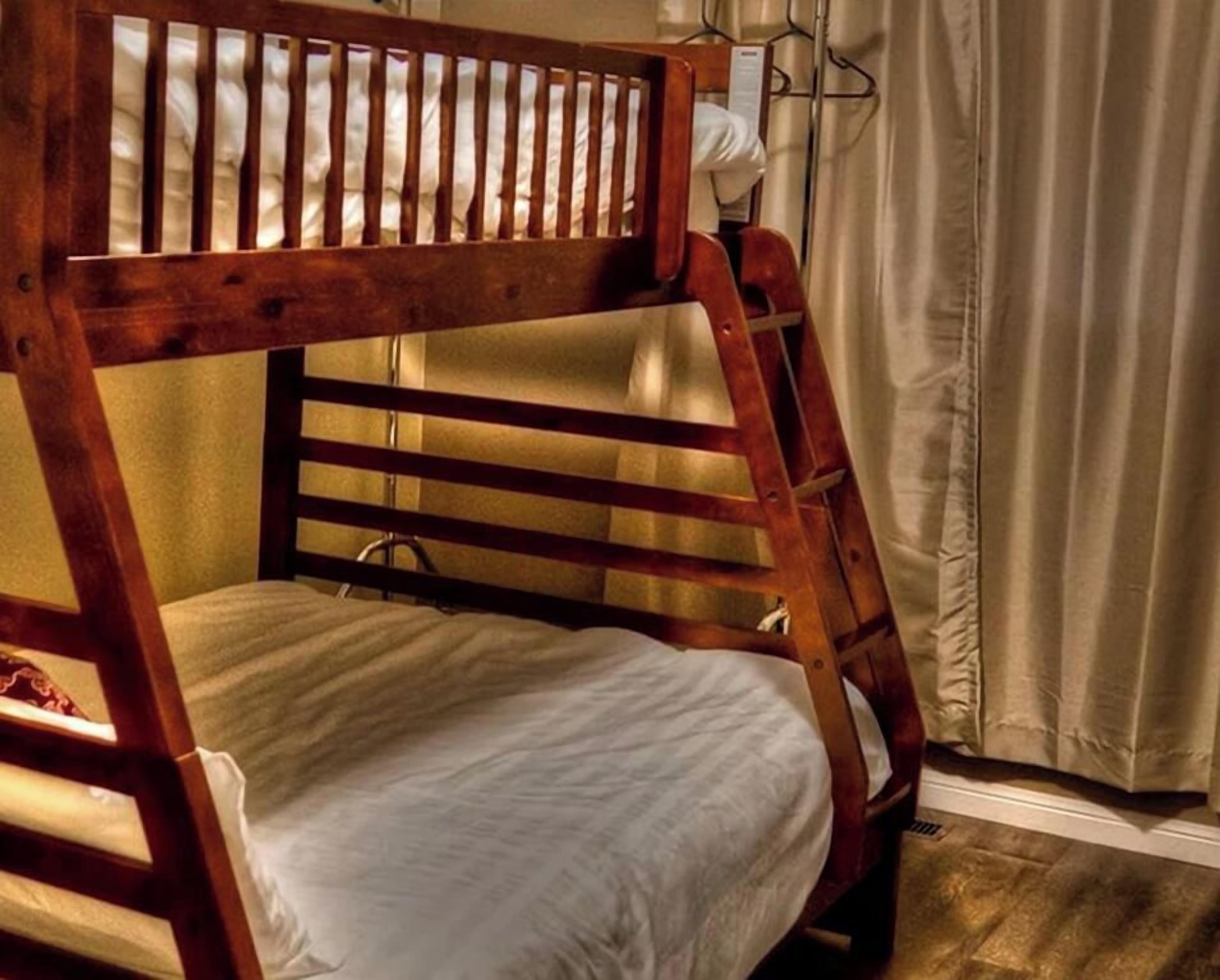 A bunk bed with a ladder, a white pillow, and a curtain in a room.