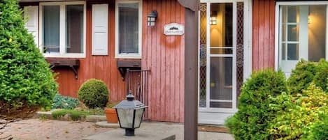 A wooden house with a porch, a sign, and a well-maintained garden.