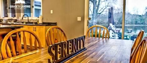 Un coin repas avec une table en bois, des chaises et une pancarte indiquant « Sérénité ».