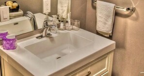 Une salle de bain avec un lavabo blanc, un miroir et un porte-serviettes.
