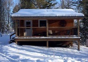A wooden cabin with a covered porch, a door, and windows.