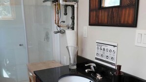 Un baño con lavamanos de encimera negro, un espejo y zona de ducha.