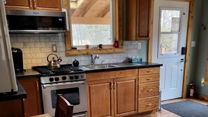 Cocina compacta con armarios de madera, horno empotrado, estufa y ventana sobre el lavamanos.