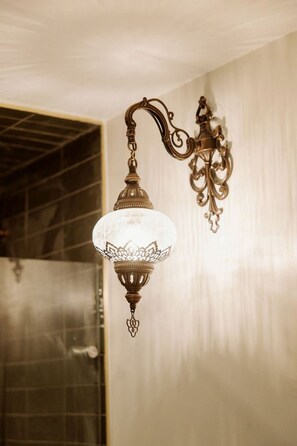 Una lámpara de pared con pantalla de vidrio y detalles metálicos ornamentales.