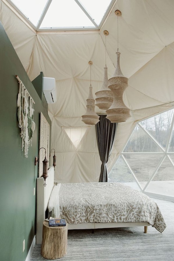 A tent-style room with a bed, hanging lamps, and a view through the window.