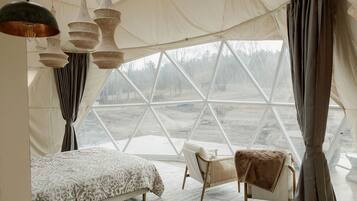 A tent-style room with a bed, two chairs, and hanging light fixtures.