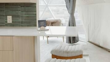 A tented room with a wooden bench, a white table, and a hanging pendant light.
