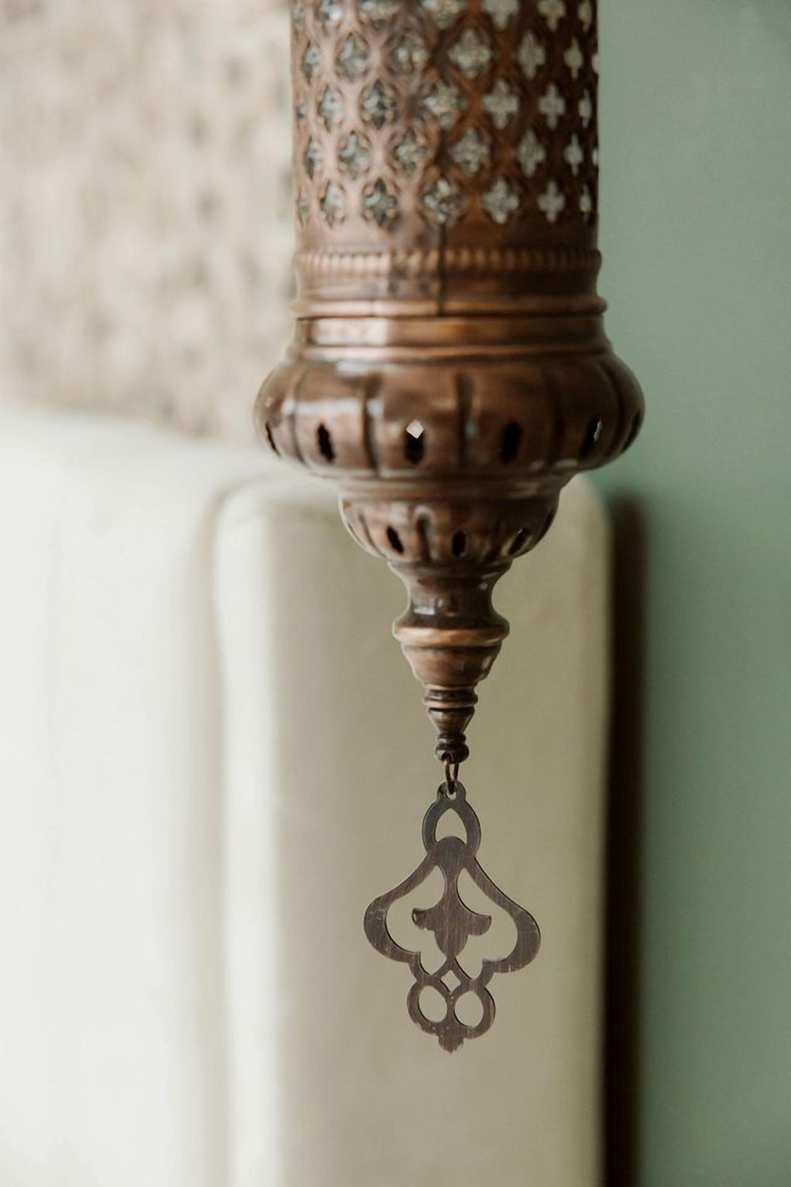 A close-up of a decorative metal lamp with intricate patterns and a hanging ornament.