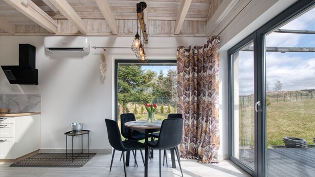 A modern kitchen with a dining area, large windows, and a view of the outdoors.