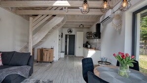 A modern interior with a staircase, a dining area with a vase of flowers, and a kitchen in the background.