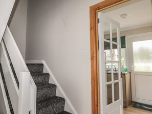 A staircase with carpeted steps leading to a room with a window and a door. - Taigh Ban (Nairn)