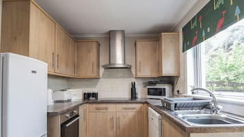 A kitchen with wooden cabinets, a stainless steel range hood, a microwave, a dishwasher, and a sink.