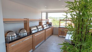 Cocina moderna con armarios de madera, encimera negra y un amplio ventanal con vistas al verdor.