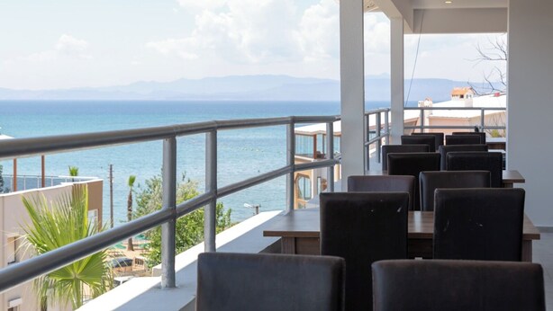 Un restaurante con terraza al aire libre con vistas al mar, que ofrece una vista de la costa y las montañas.